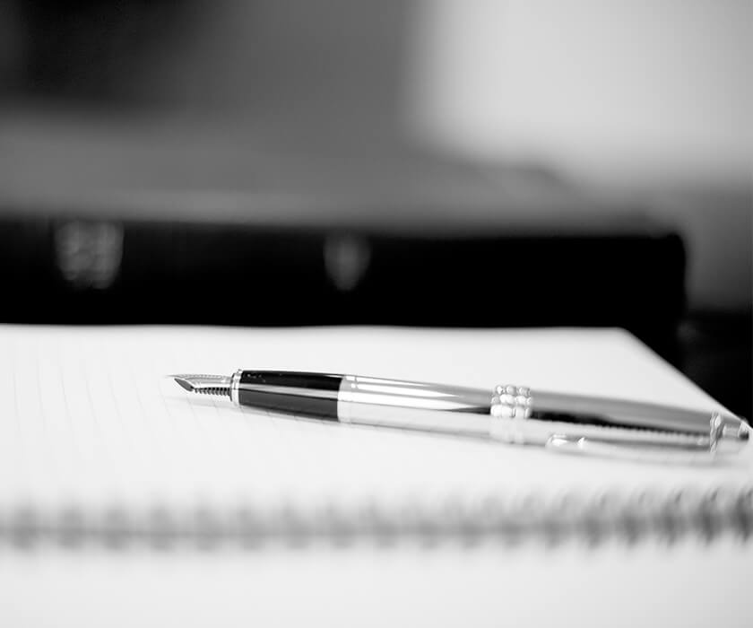 Close up of a sliver fountain pen on a clear notebook with blurred background